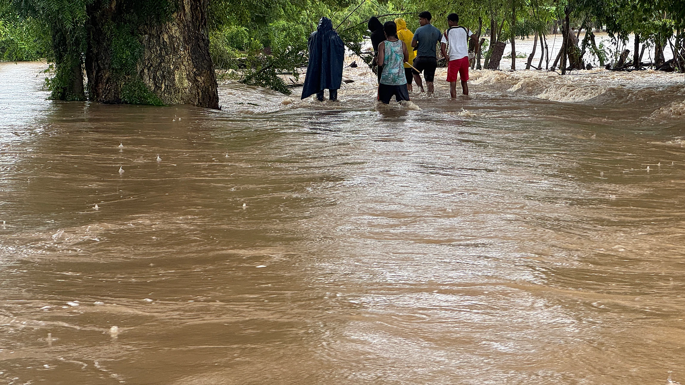 Personas caminan por una calle inundada tras el paso del huracán 'John', este sábado en el municipio de Coicoyán de Las Flores (México). 