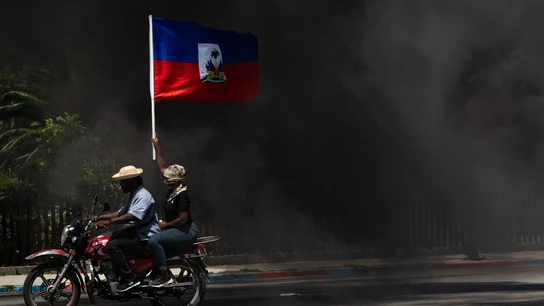 Fotografía de archivo de una persona que ondea una bandera haitiana en medio del humo, durante una marcha para exigir seguridad contra las pandillas Fotografía de archivo de una persona que ondea una bandera haitiana en medio del humo, durante una marcha para exigir seguridad contra las pandillas