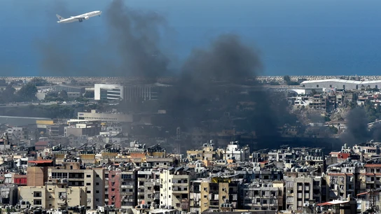 Un avión vuela en medio del humo que se eleva sobre la ciudad tras un ataque aéreo israelí en el bastión de Hizbulá Un avión vuela en medio del humo que se eleva sobre la ciudad tras un ataque aéreo israelí en el bastión de Hizbulá