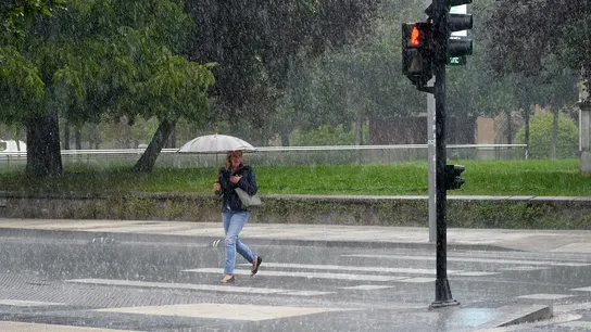 Imagen de archivo. Una mujer se protege de la lluvia con un paraguas. Imagen de archivo. Una mujer se protege de la lluvia con un paraguas.