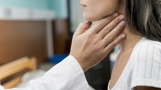 Una médico examinando el tiroides de una paciente. Tiroides
