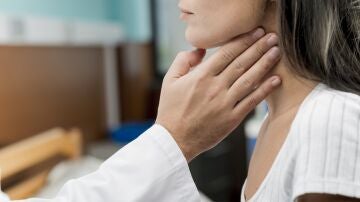 Una médico examinando el tiroides de una paciente.