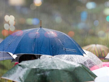 Lluvia en la ciudad y gente con paraguas