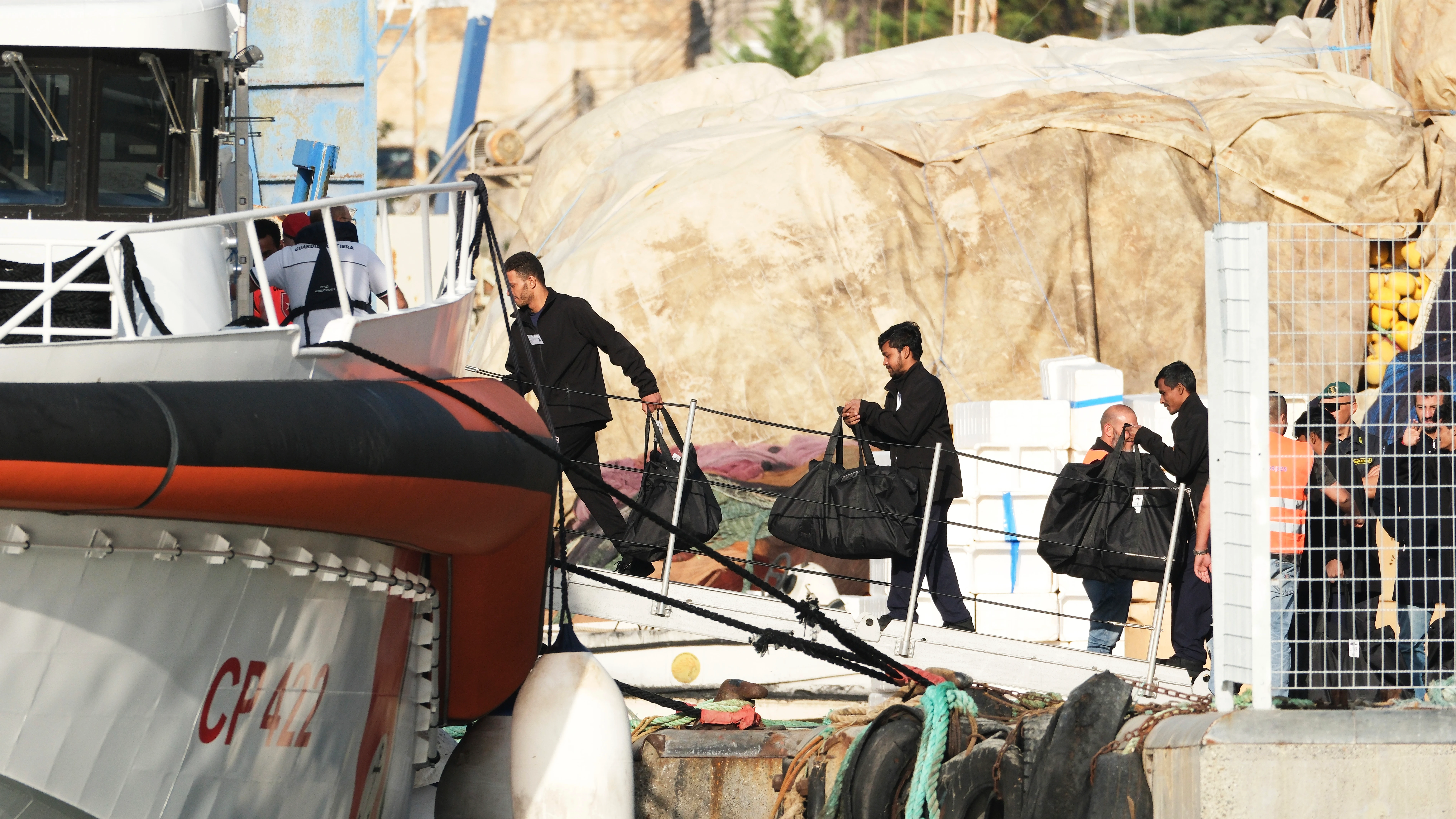 Los migrantes abordan un barco de la guardia costera italiana en el puerto de Shengjin, Albania, con destino a Italia.