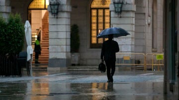 Imagen de archivo de una persona protegiéndose de la lluvia.