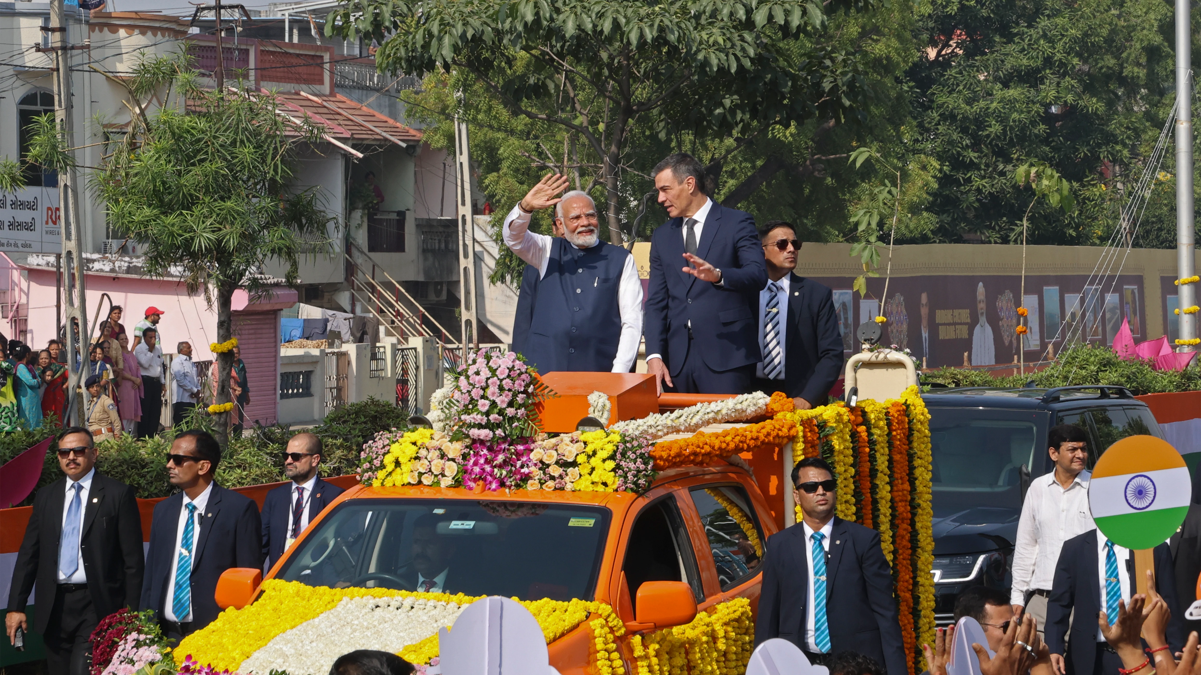 Narendra Modi y Pedro Sánchez saludan a la gente desde un vehículo en Vadodara.