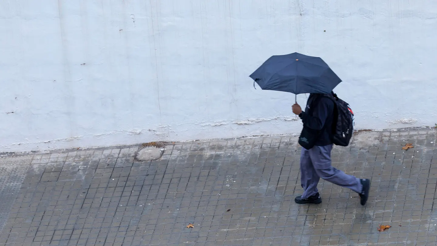 Un joven se protege de la lluvia con un paraguas en Valencia, en una imagen de archivo Un joven se protege de la lluvia con un paraguas en Valencia, en una imagen de archivo