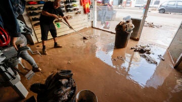 Un hombre retira el lodo acumulado en el interior de su comercio en la localidad valenciana de Catarroja, tras las intensas lluvias caídas por la fuerte dana. 