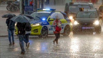 Varias personas se protegen de la lluvia en la Plaza de Espanya de Barcelona