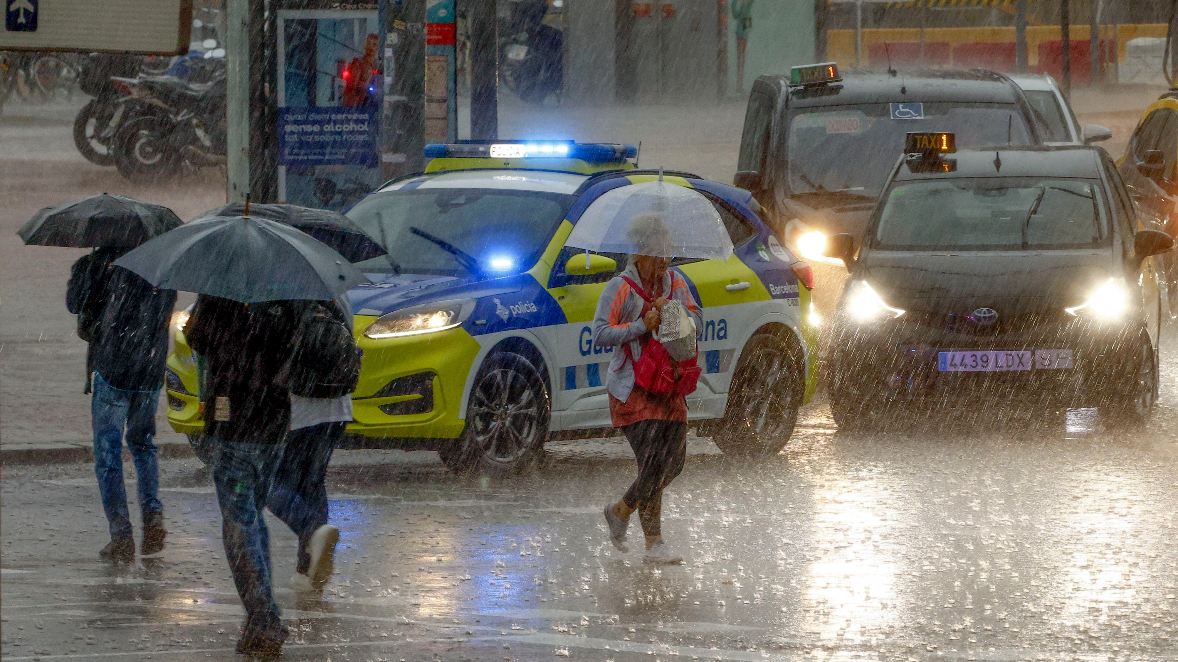 Varias personas se protegen de la lluvia en la Plaza de Espanya de Barcelona