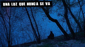 Hombre sentado junto a un r&iacute;o.