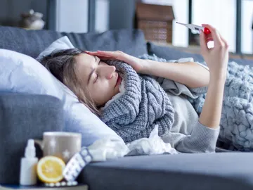 Una mujer en el sofá con un resfriado Una mujer en el sofá con un resfriado
