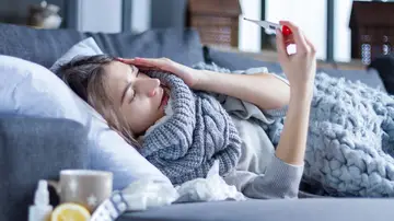 Una mujer en el sofá con un resfriado Una mujer en el sofá con un resfriado
