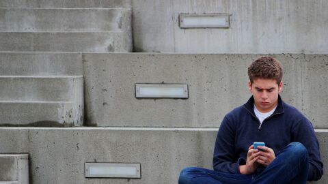 Imagen de archivo de un adolescente viendo el móvil