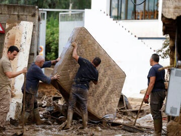 Vecinos sacan a la calle enseres dañados por las inundaciones en la localidad malagueña de Benamargosa, este jueves.