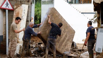 Vecinos sacan a la calle enseres dañados por las inundaciones en la localidad malagueña de Benamargosa, este jueves.