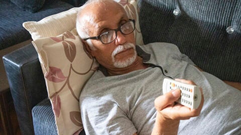 Hombre mayor tumbado viendo la televisión