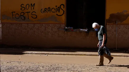 Un hombre camina por una calle cubierta de lodo Un hombre camina por una calle cubierta de lodo