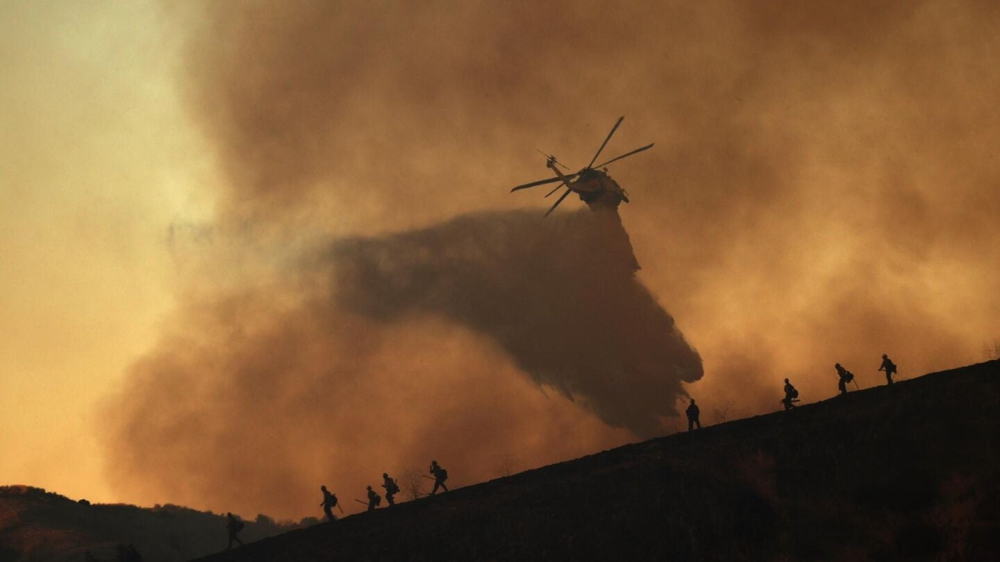 Un helicóptero arroja agua sobre el incendio Kenneth en el barrio de Woodland Hills de Los Ángeles, el 09 de enero.
