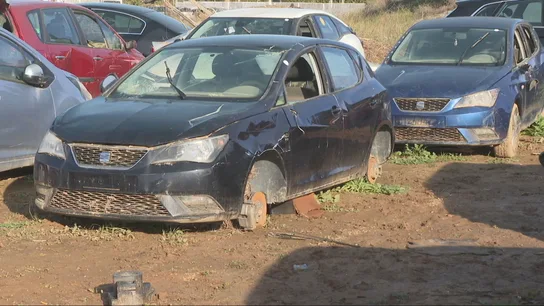 Un coche sin ruedas en una campa en Paiporta Un coche sin ruedas en una campa en Paiporta
