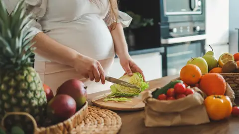Mujer embarazada preparando una ensalada Mujer embarazada preparando una ensalada