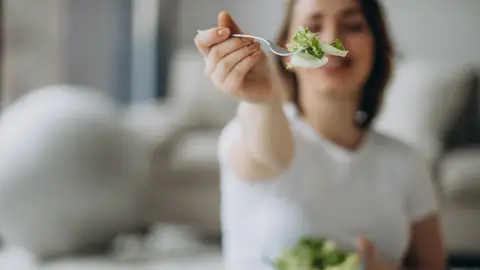Una persona comiendo ensalada.  Una persona comiendo ensalada.