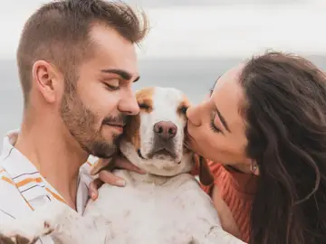 Perro besado por sus humanos Perro besado por sus humanos