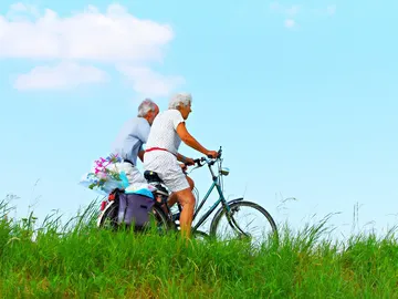 Dos personas mayores en bicicleta por el campo Dos personas mayores en bicicleta por el campo