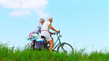 Dos personas mayores en bicicleta por el campo