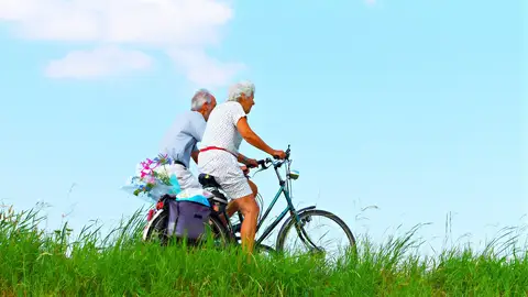 Dos personas mayores en bicicleta por el campo Dos personas mayores en bicicleta por el campo