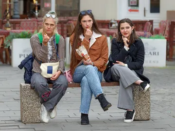 Mujeres sentadas en un banco comiendo Mujeres sentadas en un banco comiendo