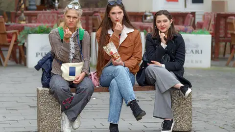 Mujeres sentadas en un banco comiendo Mujeres sentadas en un banco comiendo