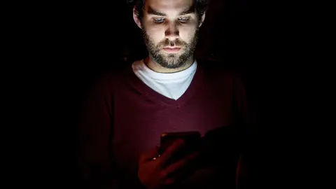 Persona mirando el móvil de noche Persona mirando el móvil de noche