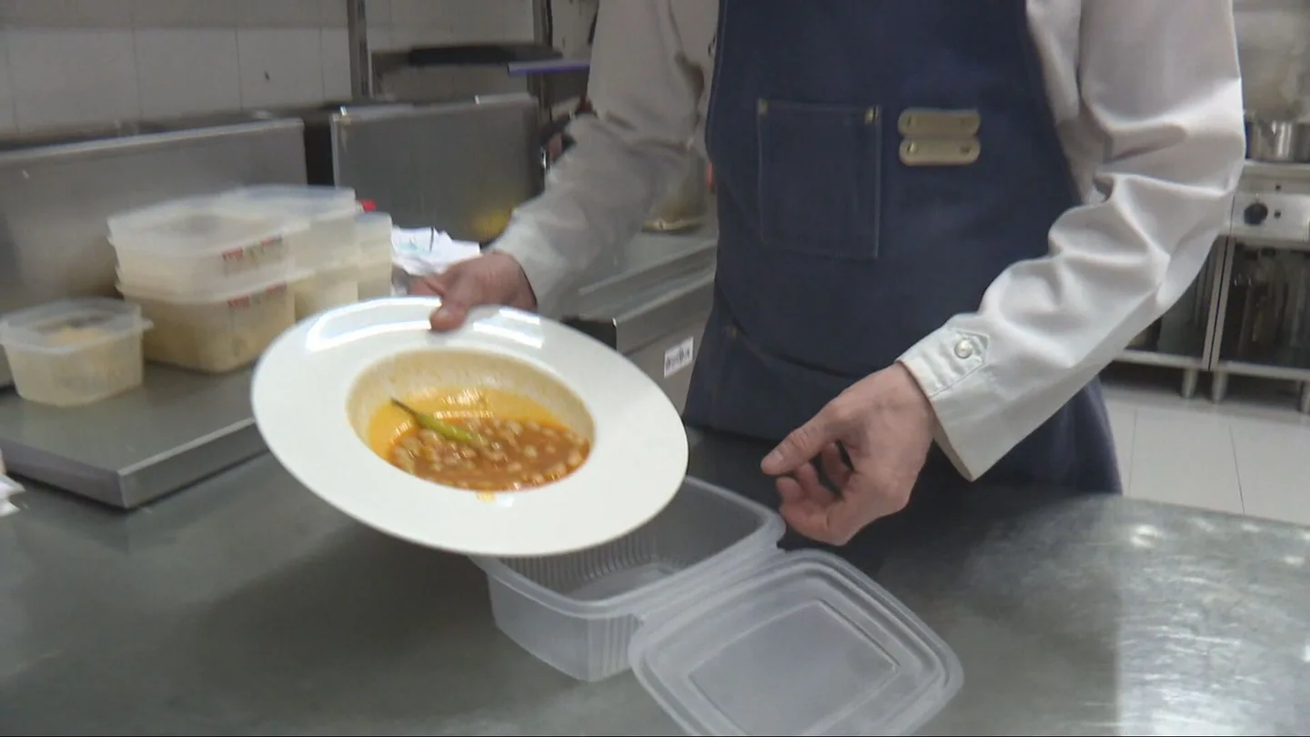 Un cocinero guarda en un tupper comida Un cocinero guarda en un tupper comida