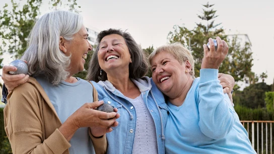 Los cambios en la jubilación que podrían beneficiar especialmente a las mujeres. Tres mujeres jubiladas sonríen y se abrazan mientras pasan tiempo juntas.