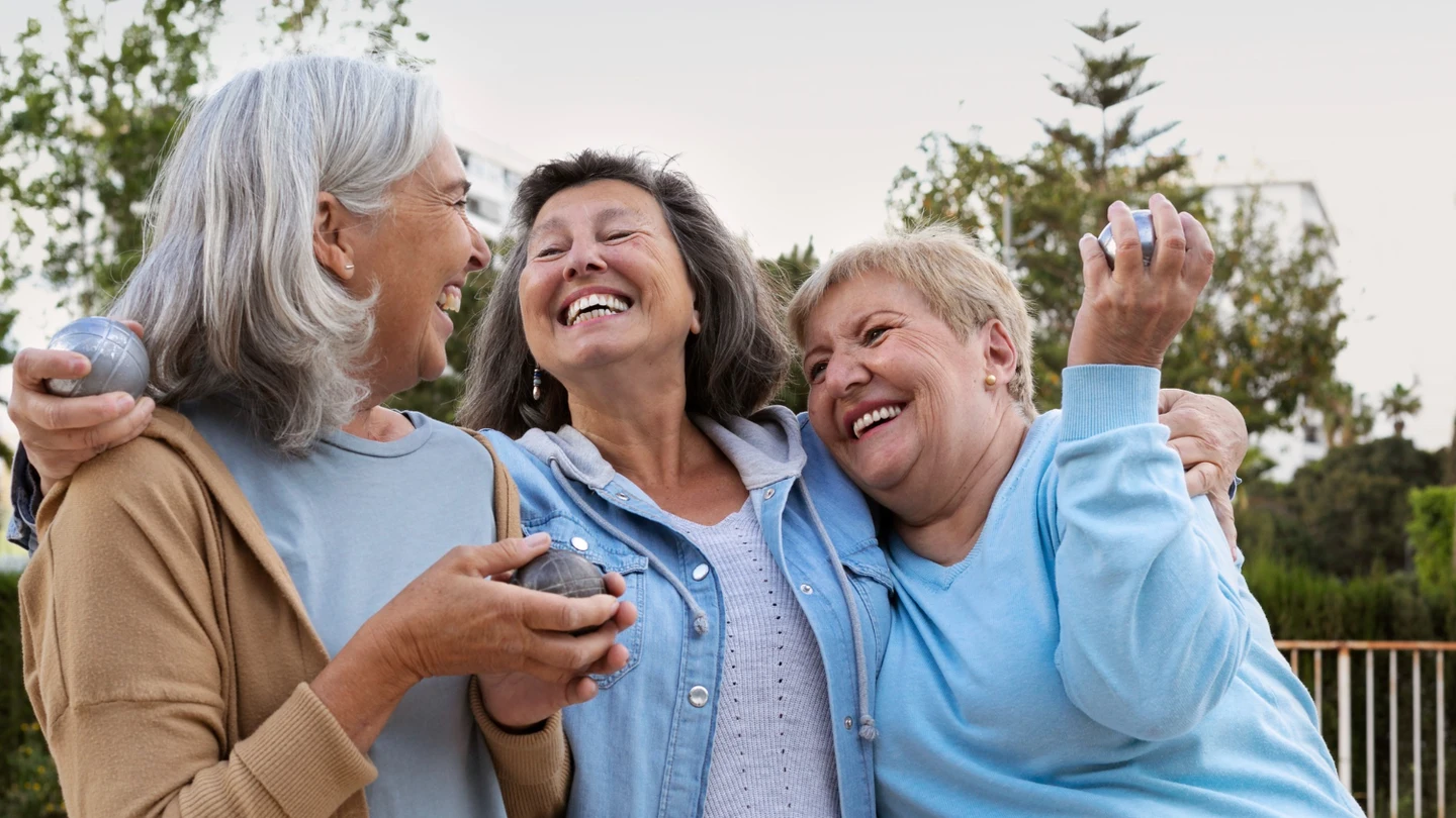 Los cambios en la jubilación que podrían beneficiar especialmente a las mujeres. Tres mujeres jubiladas sonríen y se abrazan mientras pasan tiempo juntas.