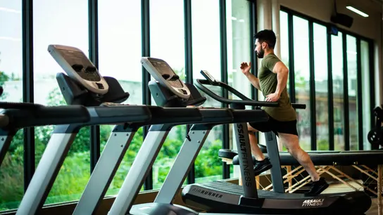 Un señor corriendo en una cinta en un gimnasio Un señor corriendo en una cinta en un gimnasio