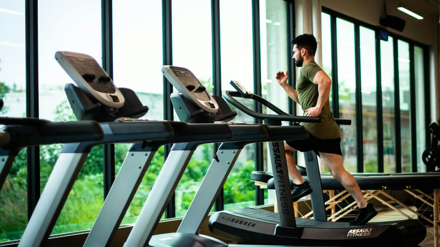 Un señor corriendo en una cinta en un gimnasio Un señor corriendo en una cinta en un gimnasio