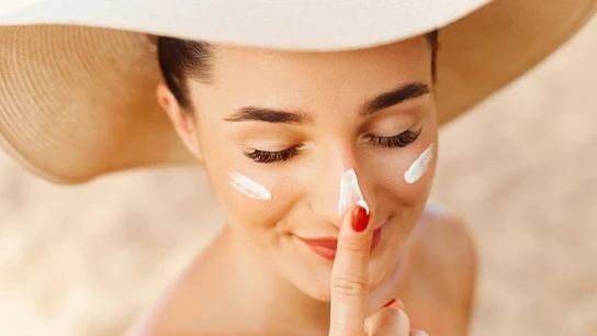 Una mujer con protección solar en la cara Cosméticos-crema solar