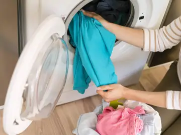 Persona recogiendo ropa de la lavadora. Persona recogiendo ropa de la lavadora.