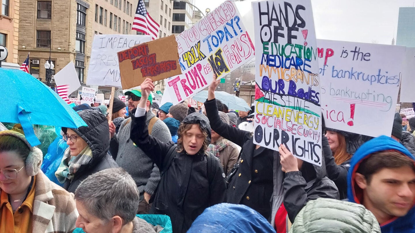  Personas sostienen carteles durante una protesta denominada 'Hands Off' este sábado, en Boston.