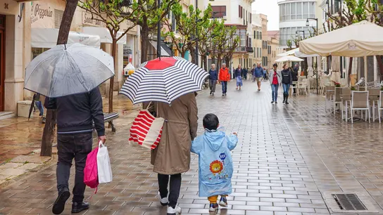 Una familia se protege de la lluvia con paraguas en el centro histórico de Mahón, Menorca. Una familia se protege de la lluvia con paraguas en el centro histórico de Mahón, Menorca.