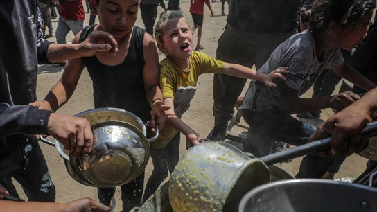 Niños palestinos que esperan recibir una ración de comida de un comedor social en un campo de refugiados en el norte de la Franja de Gaza Niños palestinos que esperan recibir una ración de comida de un comedor social en un campo de refugiados en el norte de la Franja de Gaza