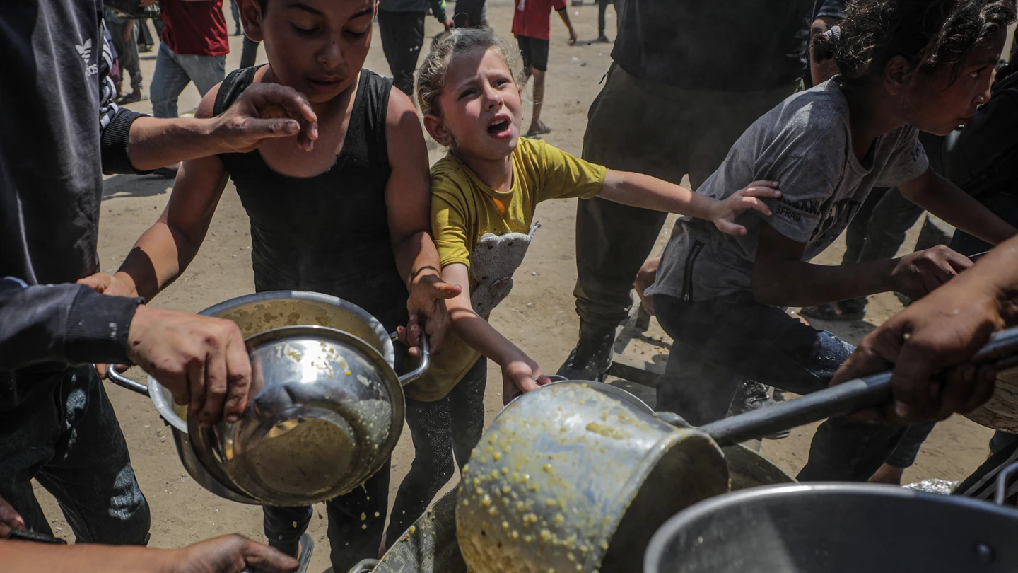 Niños palestinos que esperan recibir una ración de comida de un comedor social en un campo de refugiados en el norte de la Franja de Gaza Niños palestinos que esperan recibir una ración de comida de un comedor social en un campo de refugiados en el norte de la Franja de Gaza