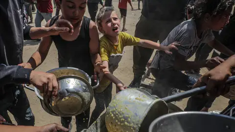 Niños palestinos que esperan recibir una ración de comida de un comedor social en un campo de refugiados en el norte de la Franja de Gaza Niños palestinos que esperan recibir una ración de comida de un comedor social en un campo de refugiados en el norte de la Franja de Gaza