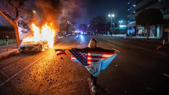 Una persona camina junto a un coche en llamas durante las protestas por las redadas de inmigración de la administración Trump en Los Ángeles Una persona camina junto a un coche en llamas durante las protestas por las redadas de inmigración de la administración Trump en Los Ángeles
