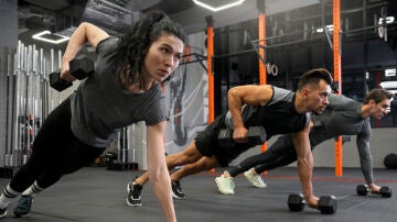 Mujeres y hombres haciendo ejercicios de fuerza en el gimnasio