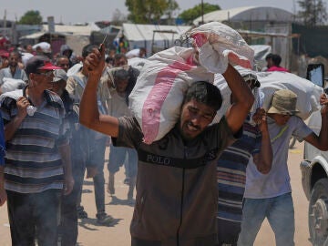 Un hombre carga con sacos de comida cerca de un punto de distribución de ayuda en Rafah, este miércoles.