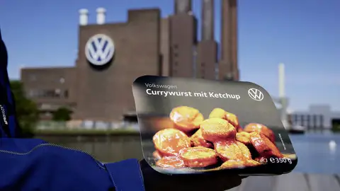 Envase de las salchichas 'Currywurst' con una fábrica de la empresa alemana de fondo Envase de las salchichas 'Currywurst' con una fábrica de la empresa alemana de fondo