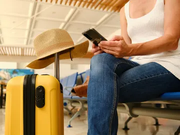 Persona con móvil y maletas Persona con móvil y maletas